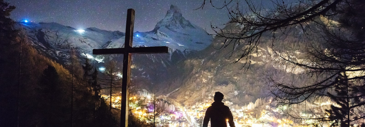 man standing near cross during night