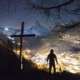 man standing near cross during night